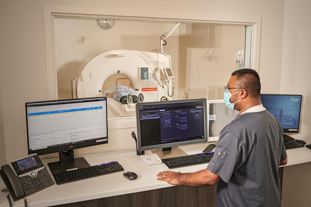 Lab Technician Monitors Screens While Patient Prepares for MRI