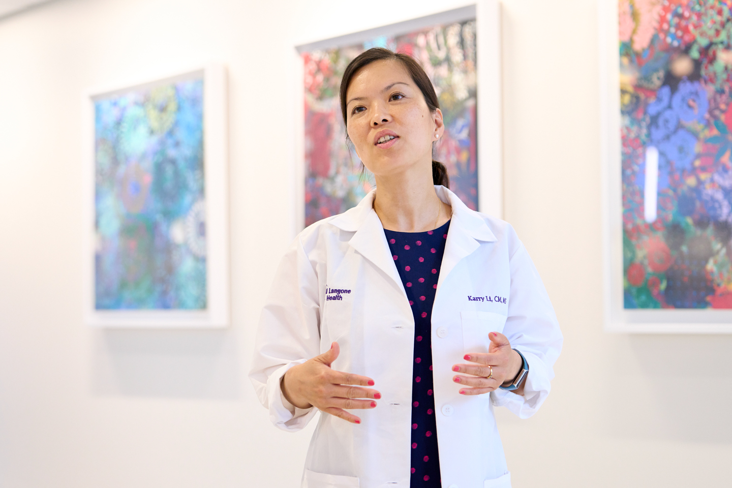 Midwife Karry Li wearing a white coat and gesturing with her hands while speaking