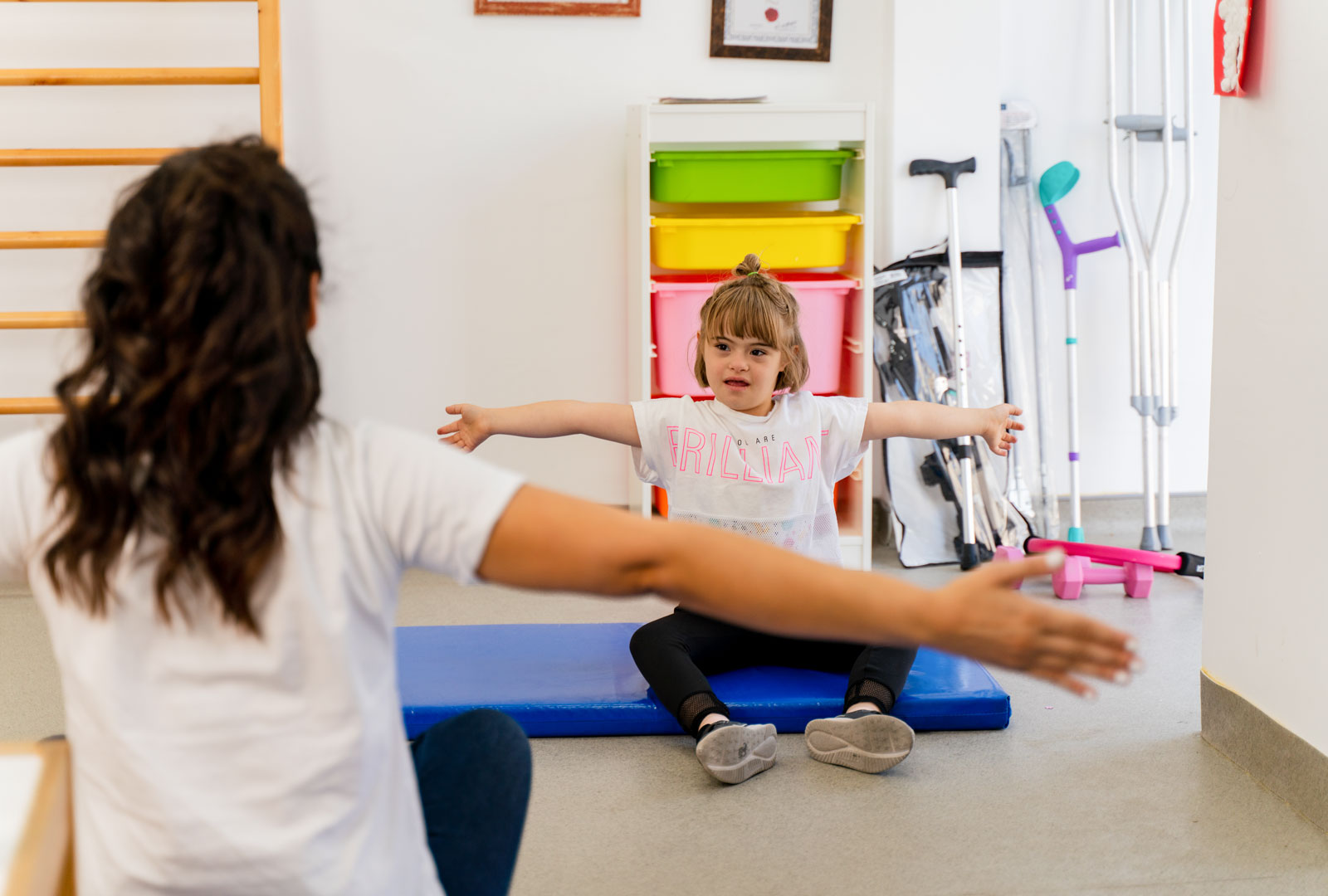 Provider with their back turned to us, leading arm exercises with seated child